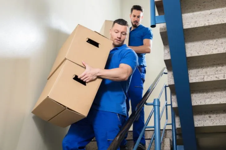 Umzugshelfer tragen Kartons im Treppenhaus Umzugshelfer tragen Kartons im Treppenhaus